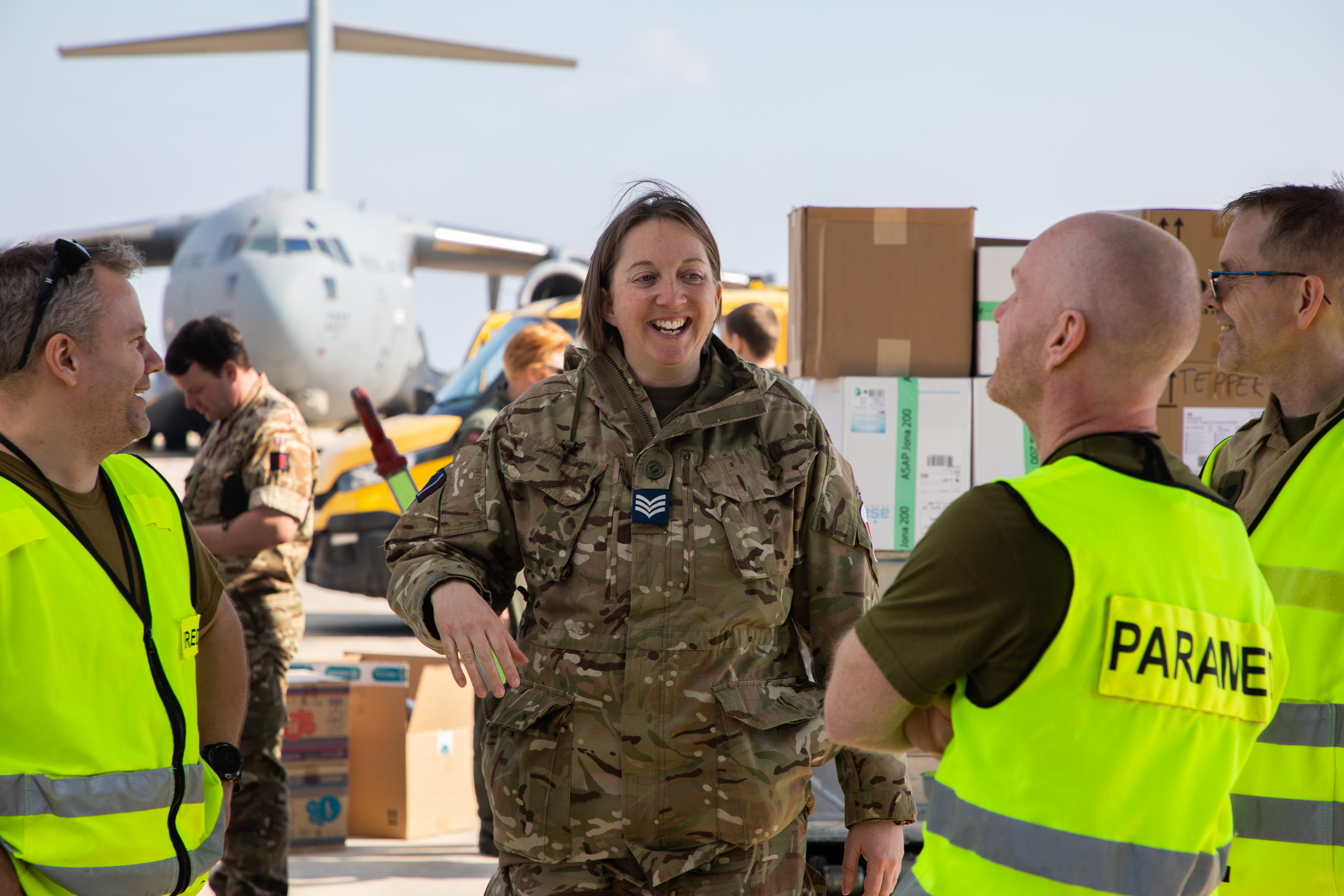 Image shows RAF medics on the airfield with RAF Hercules aircraft in the background.